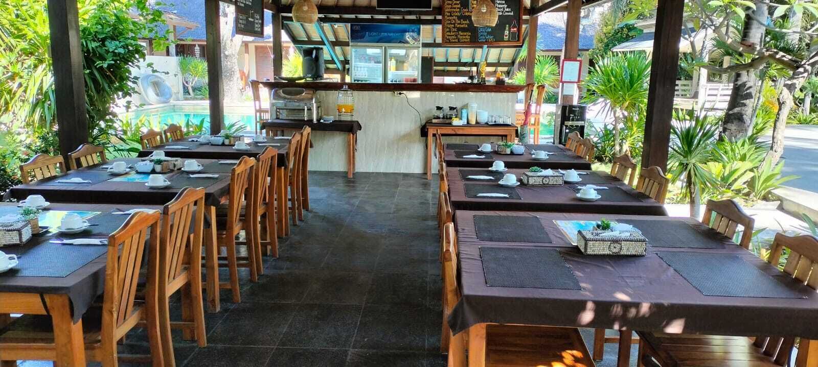 A restaurant with multiple tables and chairs, a counter with a menu, and a view of the outdoors.