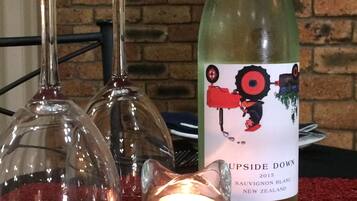 A bottle of wine, two wine glasses, and a lit candle on a red textured surface.