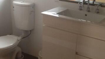 A small bathroom with a toilet, a sink, and a window above the sink.