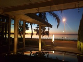 Vista desde el interior de un edificio con amplios ventanales que dan a una masa de agua tranquila al atardecer.