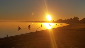 A sunset over a calm body of water with a silhouette of trees in the distance. - Barmera Lake Resort Motel (Barmera)