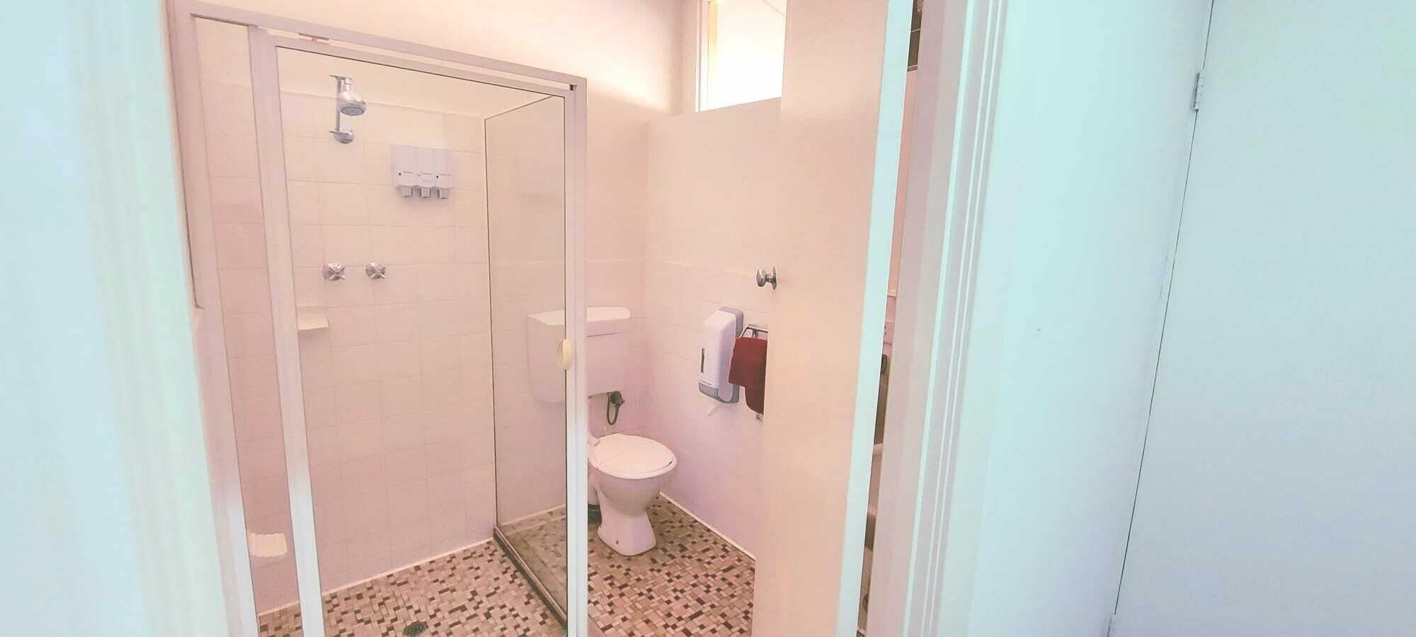 A small bathroom with a toilet, a shower, and a hand dryer.