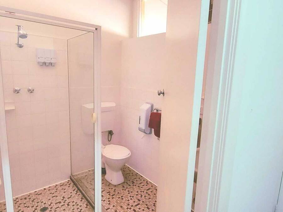 A small bathroom with a toilet, a shower, and a hand dryer.