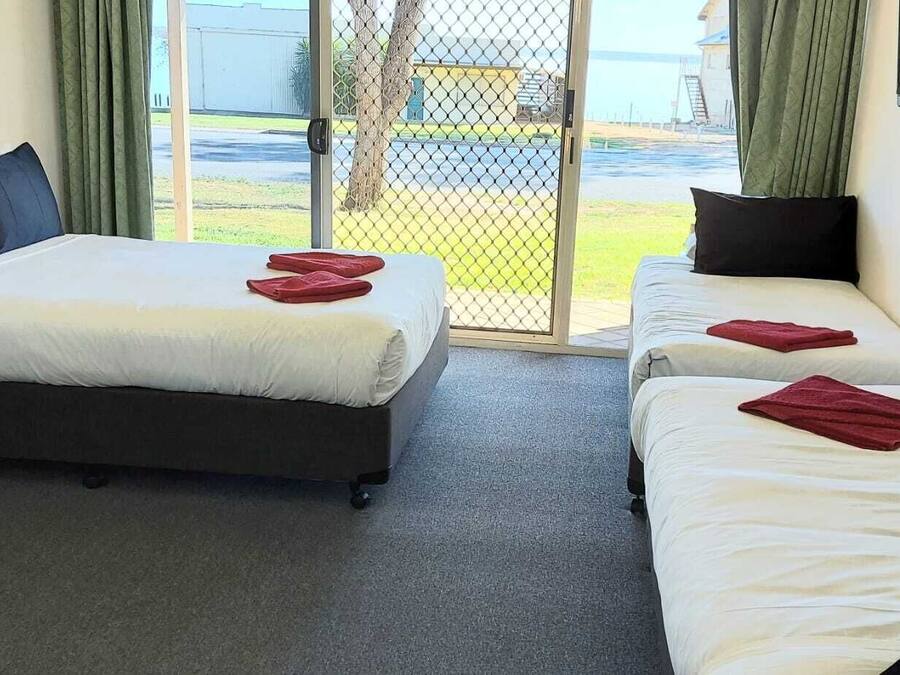 A hotel room with a single bed, a smaller bed, and a desk with a chair.