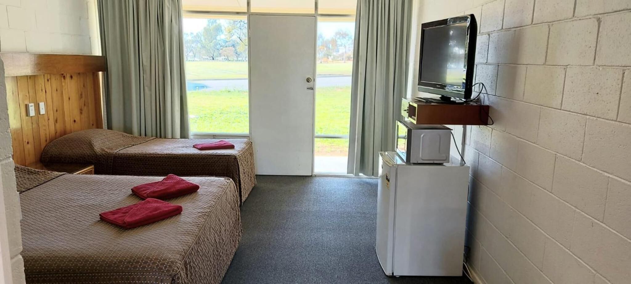 Una habitación con dos camas, televisión y refrigerador.