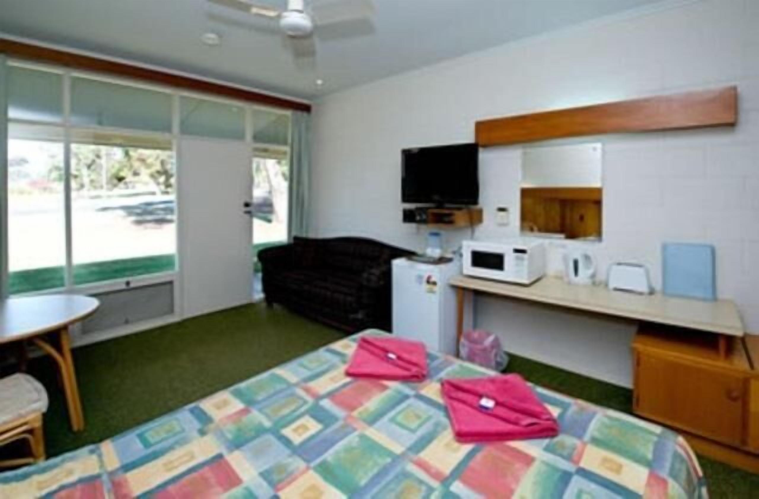 A hotel room with a bed, a desk with a computer, a television, and a window with a view of the outside.