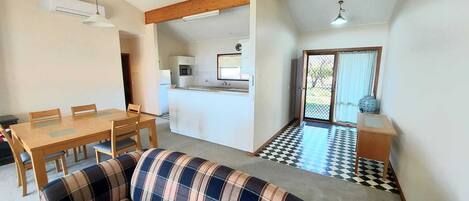 A compact living space with a dining area, a kitchenette, and a sofa.