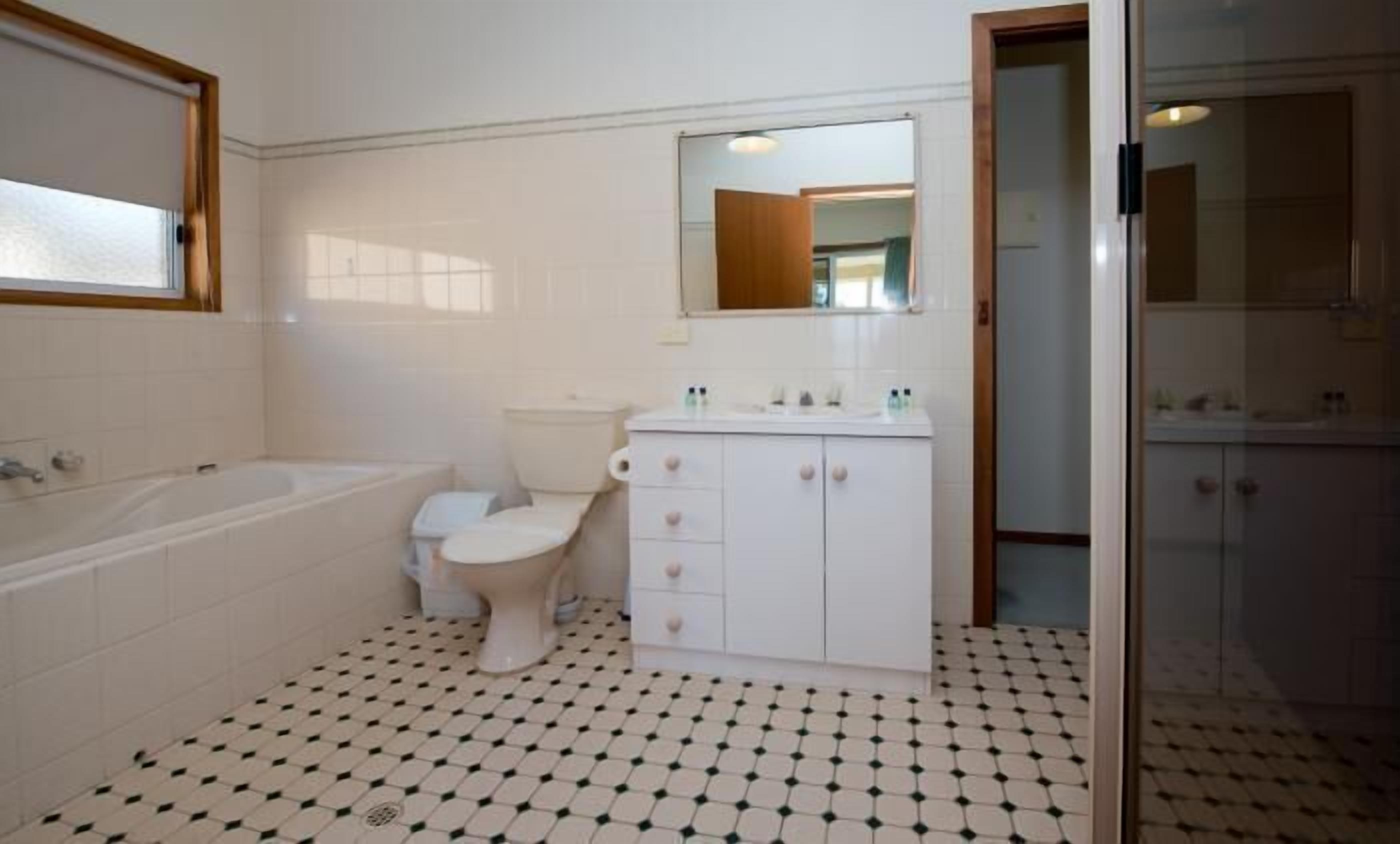 Ein Badezimmer mit einer Badewanne, Toilette und einem Waschbecken mit Spiegel darüber.