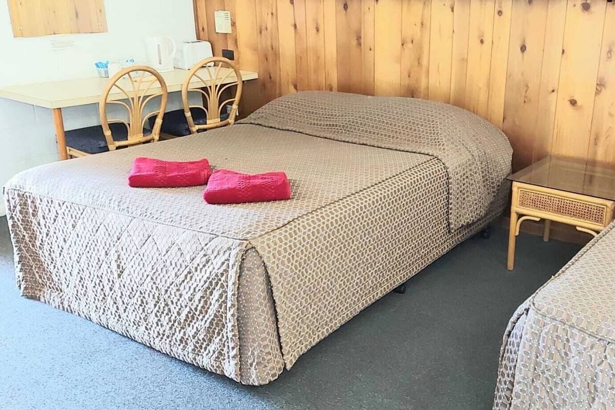 A room with two single beds, a small table, and a chair.