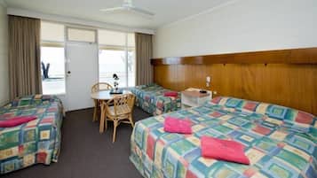 Habitación de hotel con dos camas, una mesita, una silla y un ventanal con cortinas.