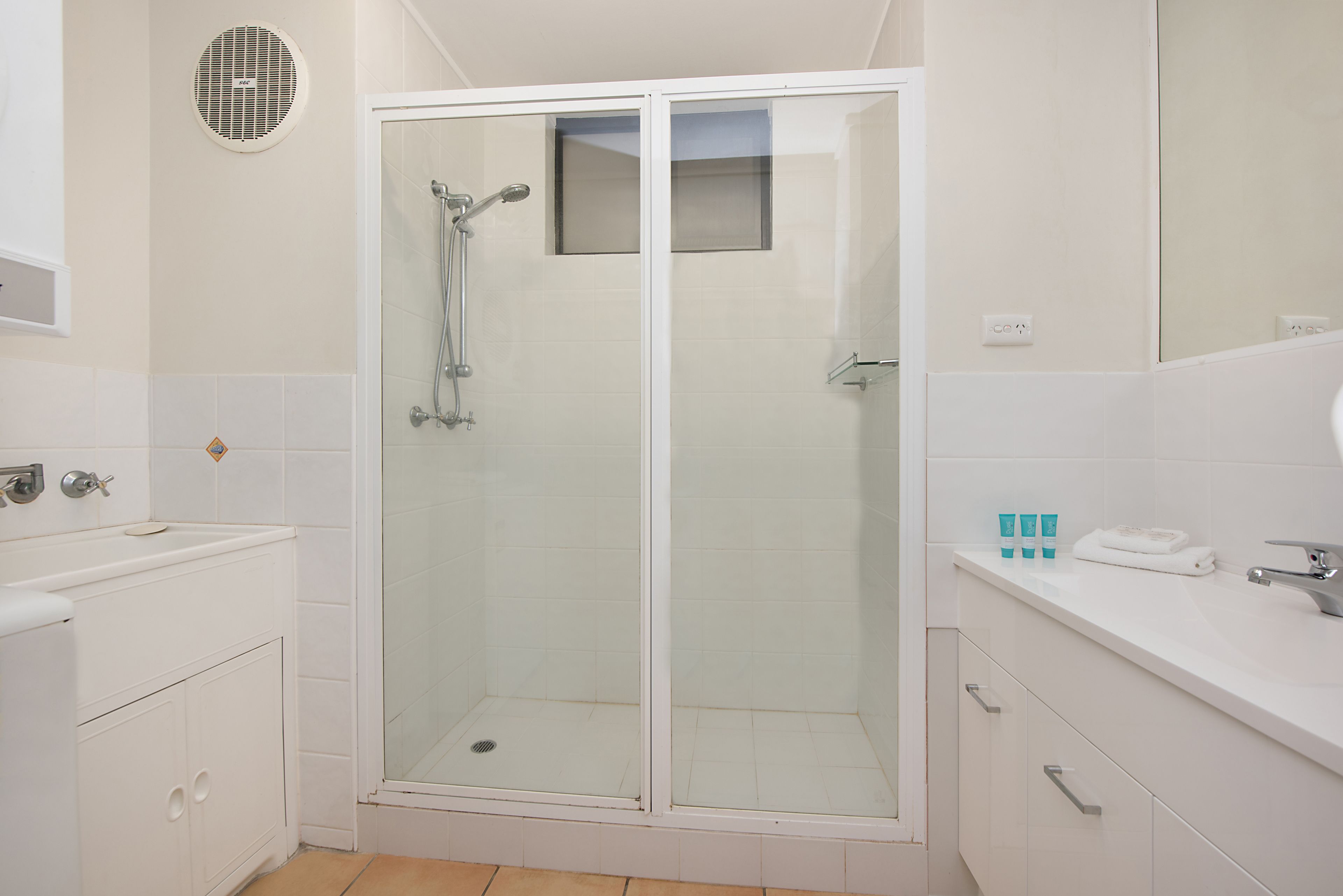 Une salle de bain moderne avec une douche à parois de verre, un lavabo blanc et un meuble-lavabo avec un miroir.