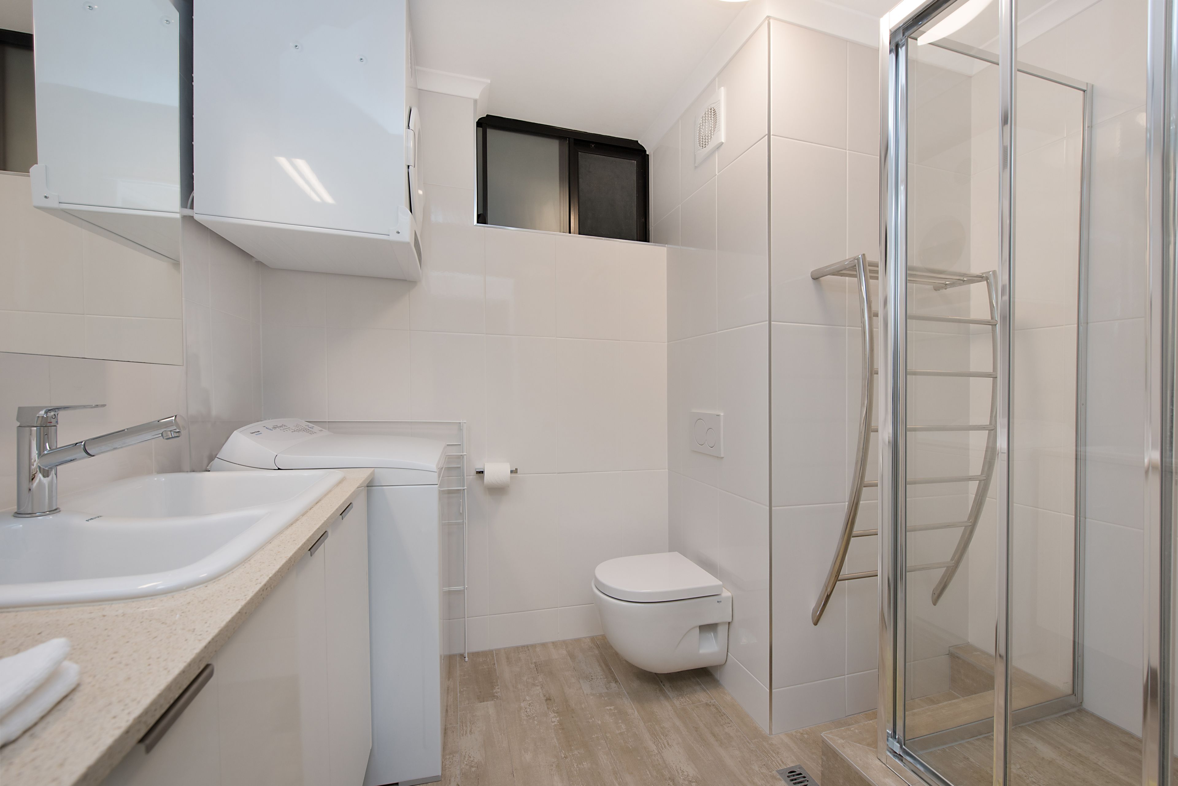 A modern bathroom with a sink, toilet, and glass shower enclosure.