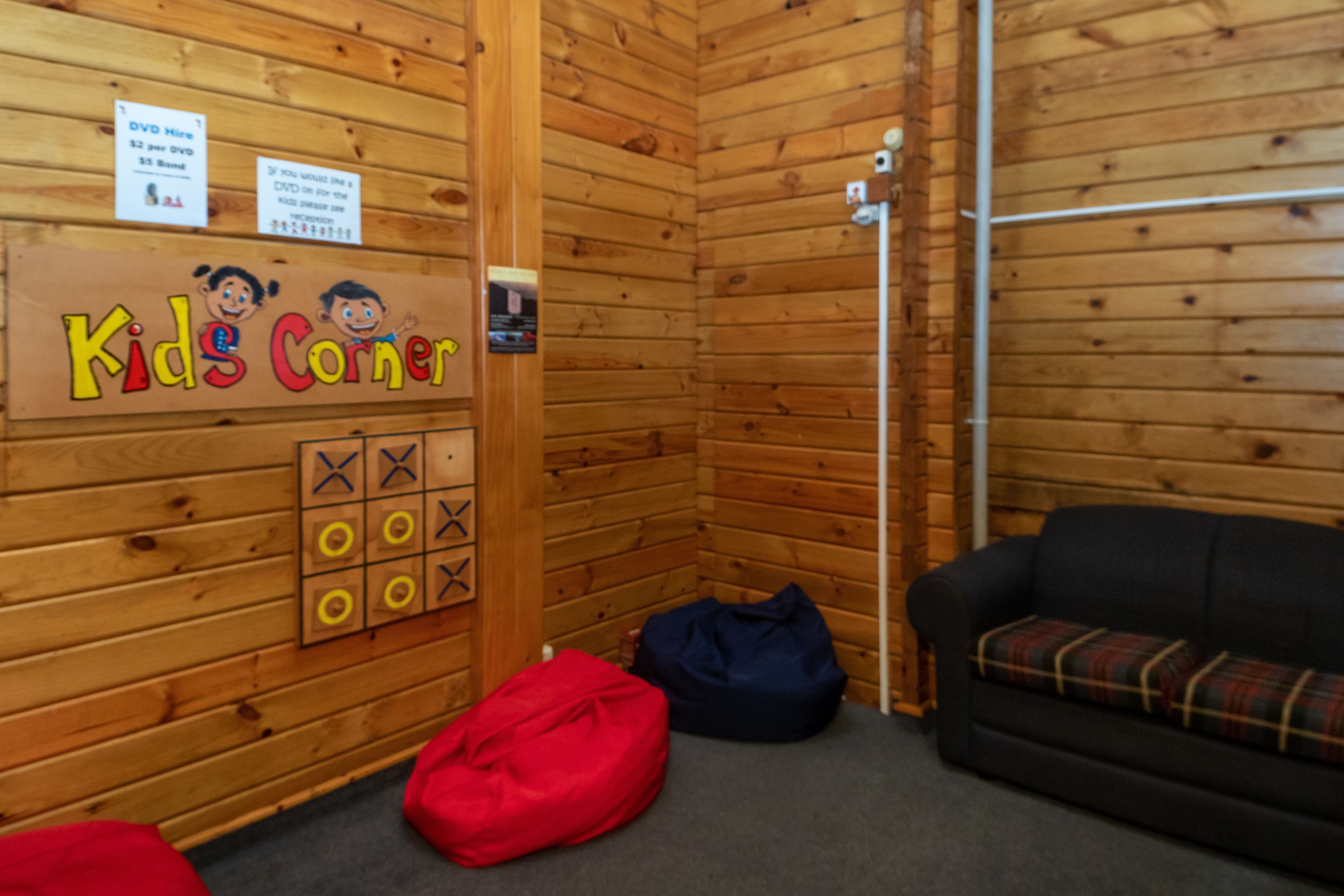 Rincón infantil con zona de juegos, sofá y pared de madera.