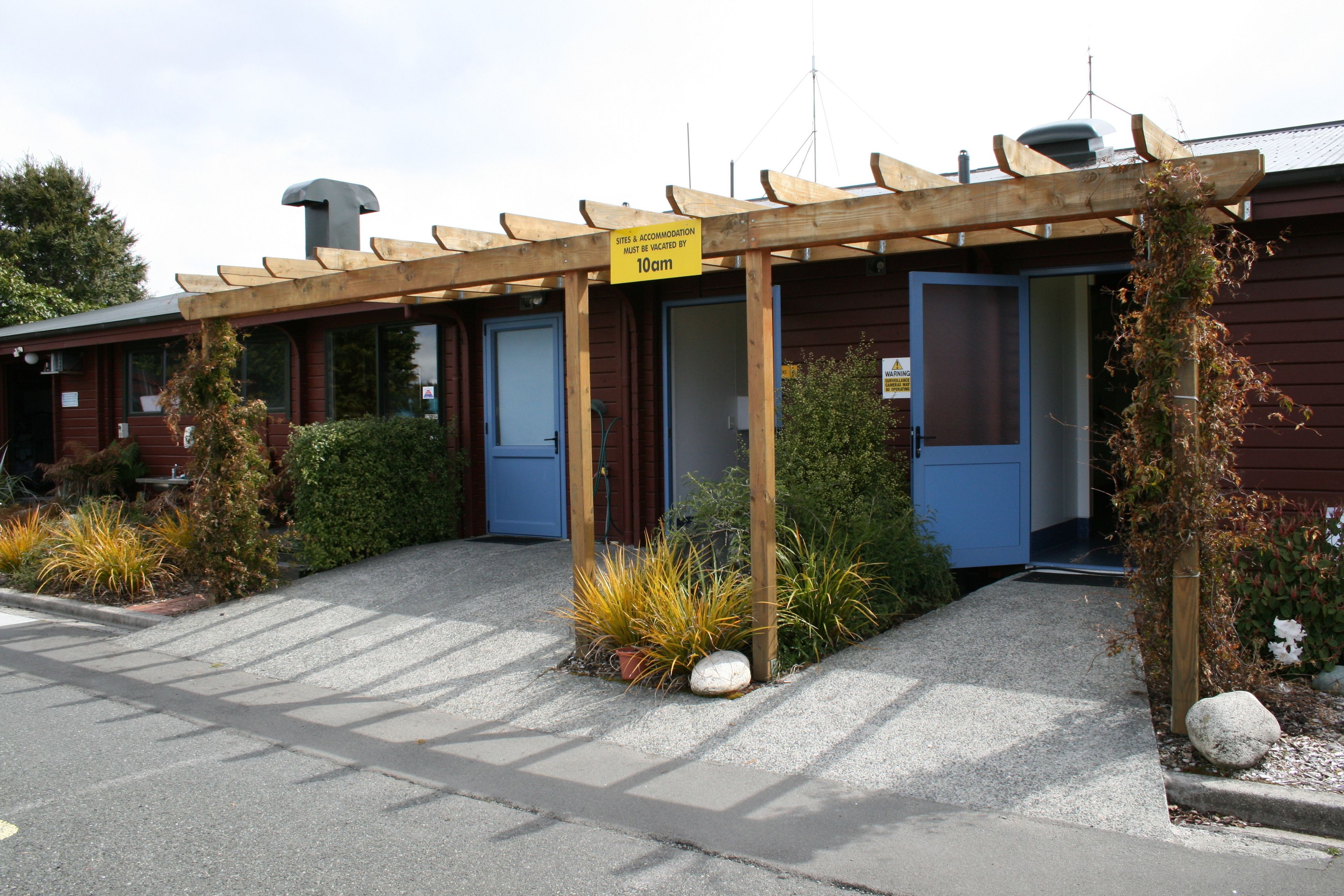 Un bâtiment doté d’un espace extérieur couvert avec des sièges et d’une pancarte indiquant que les lieux et les logements doivent être libérés avant 10 heures du matin.
