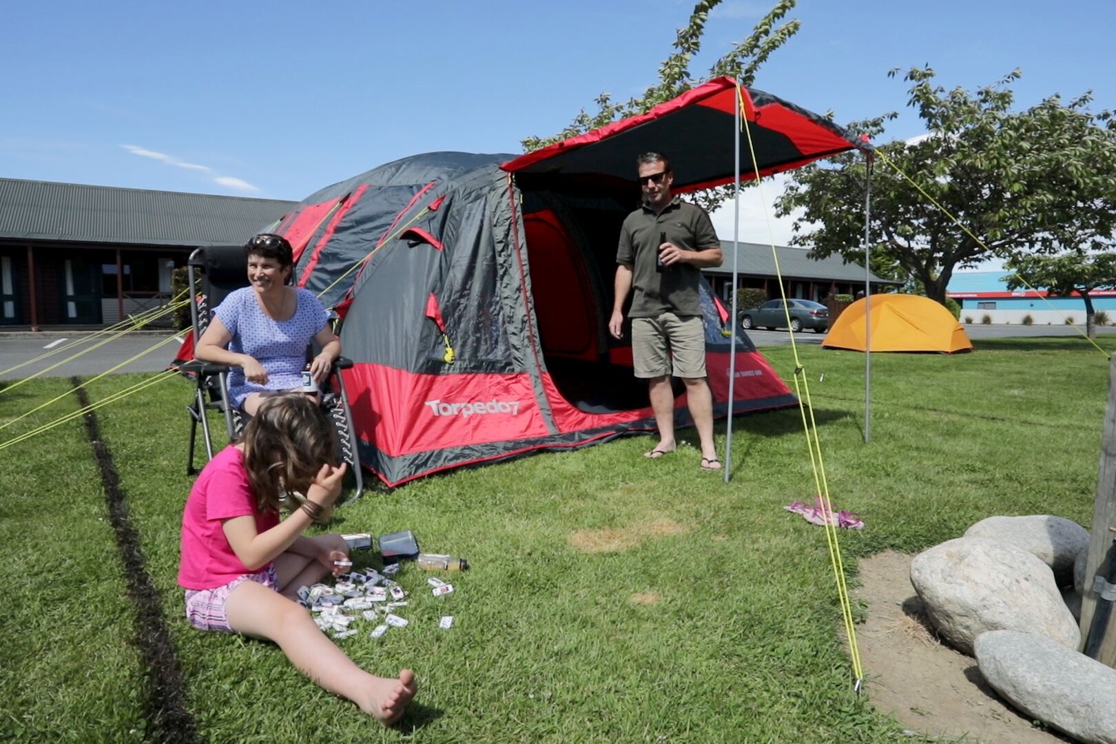 A tent set up on grass with a building in the background.