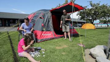 A tent set up on grass with a building in the background.