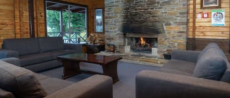 Un interior de cabaña acogedor, con chimenea de piedra, paredes de madera y una zona de estar confortable.