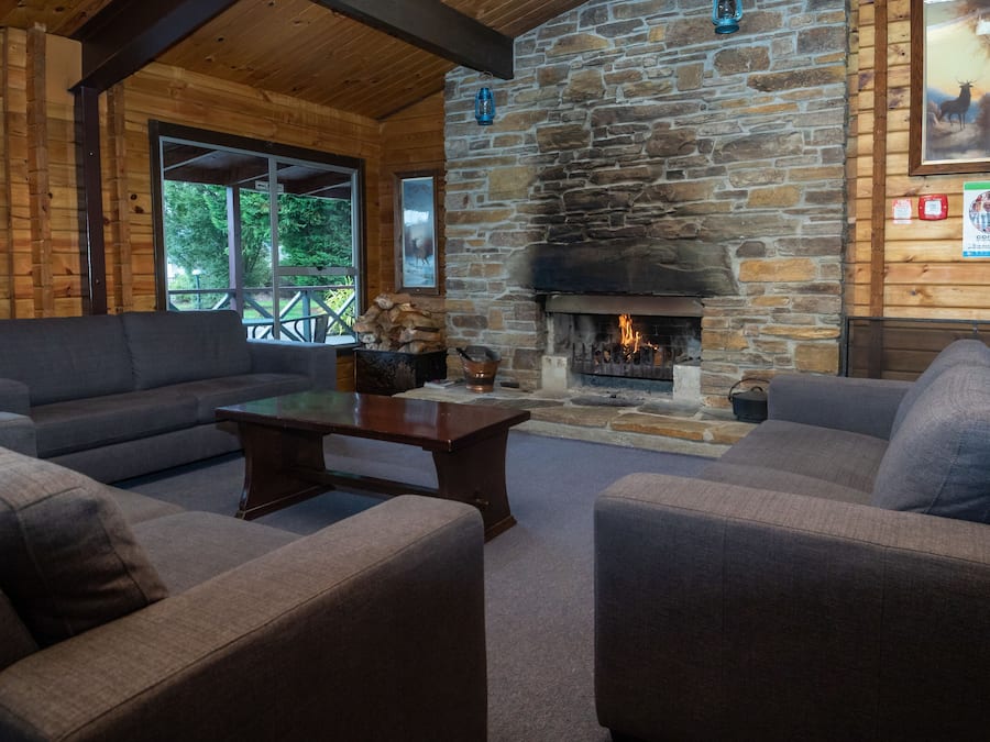 A cozy cabin interior with a stone fireplace, wooden walls, and a comfortable seating area.