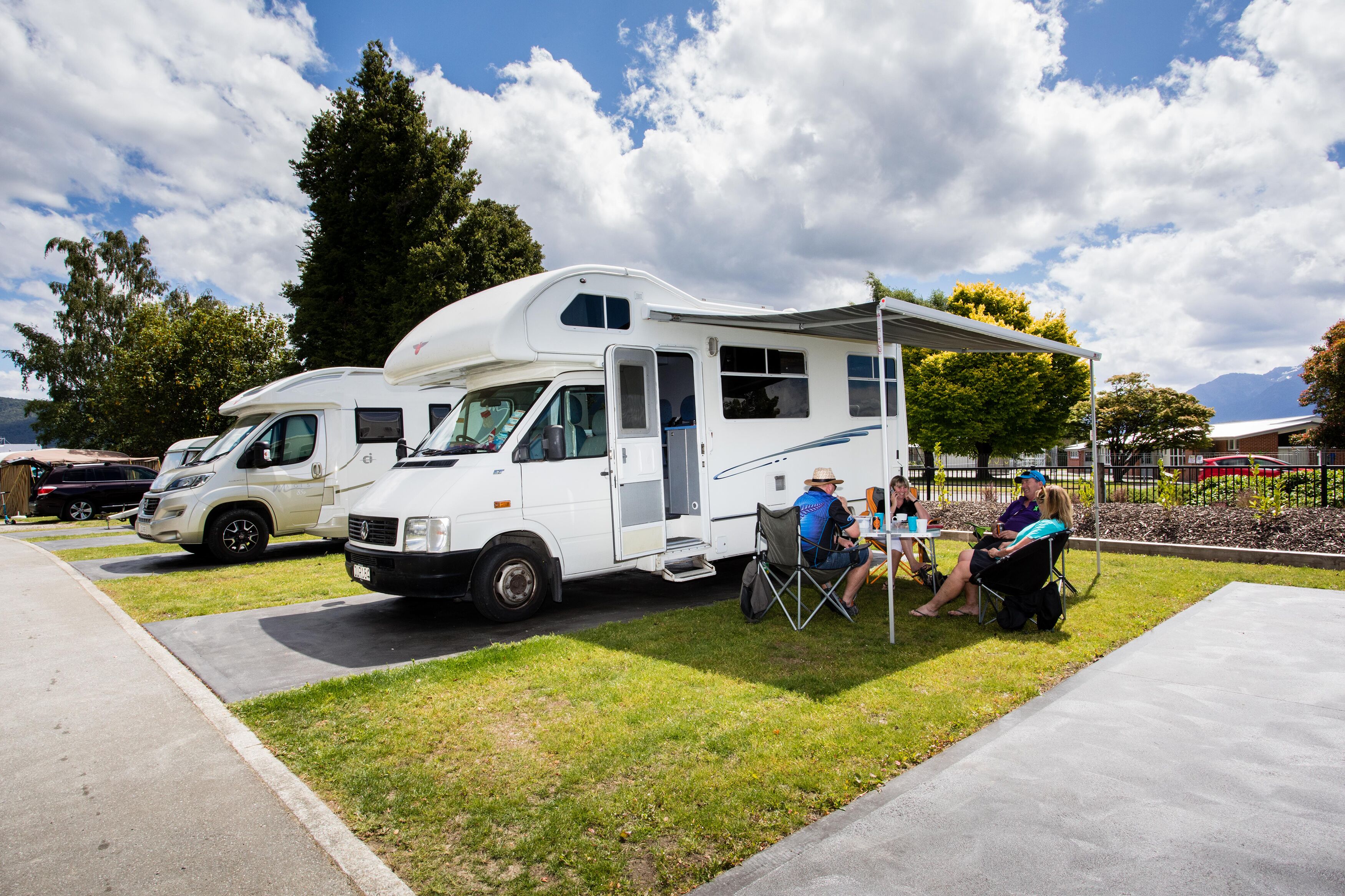 Un camping-car blanc est garé sur une pelouse, sous un ciel dégagé.
