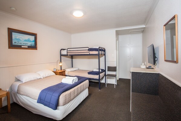 A hotel room with a bunk bed, a desk with a chair, a television, and a framed picture on the wall.