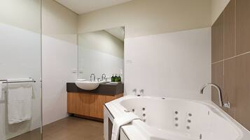 Un baño moderno con cabina de ducha de vidrio, una bañera independiente y un tocador con lavamanos dobles.