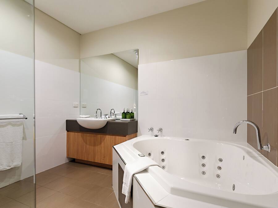Un baño moderno con cabina de ducha de vidrio, una bañera independiente y un tocador con lavamanos dobles.