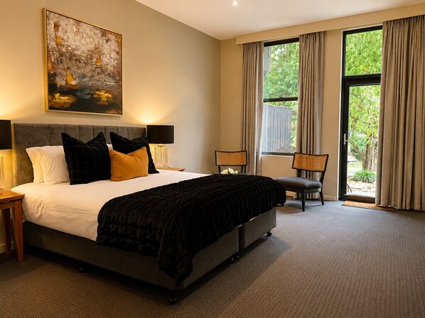 A bedroom with a large bed, two bedside tables, a chair, and a window with curtains. - The Grand Oaks Resort (Beechworth)