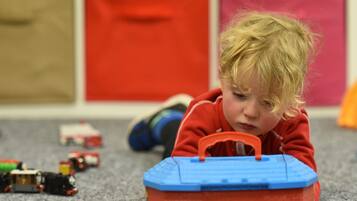 Children can play freely on the carpeted floor, surrounded by a variety of toys.