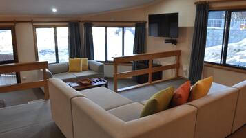 A modern living room with a sofa, a coffee table, and a TV mounted on the wall.