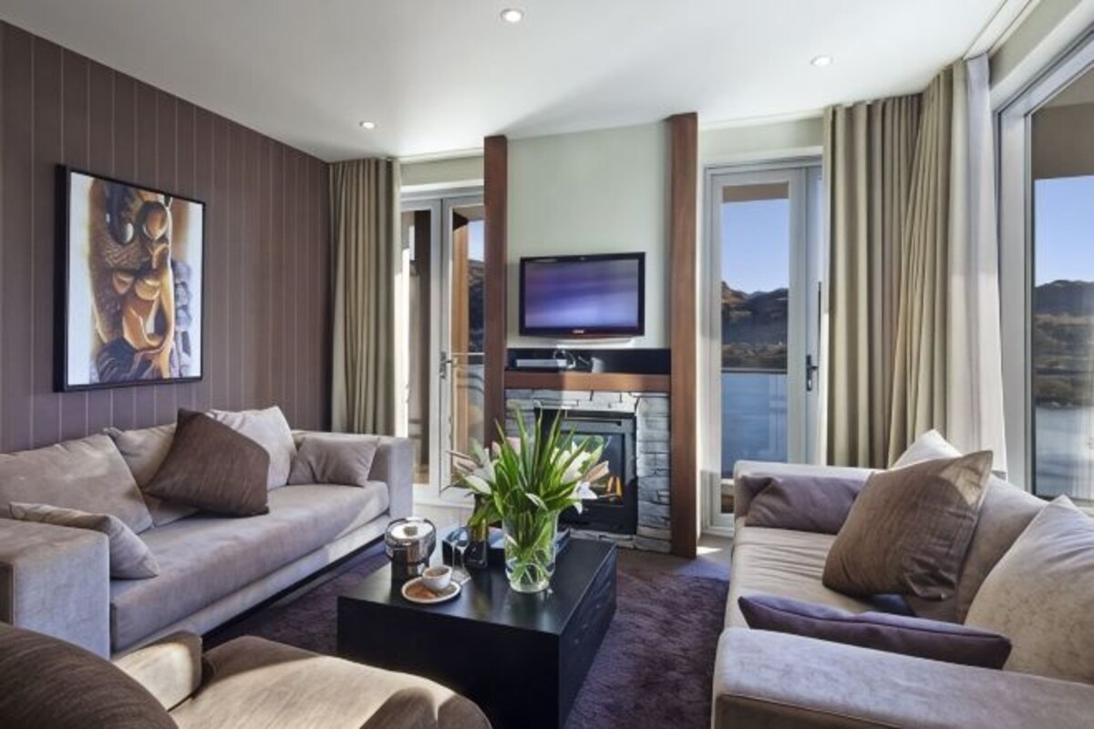 Una sala de estar moderna con chimenea, sofás, una mesa de centro y una televisión.