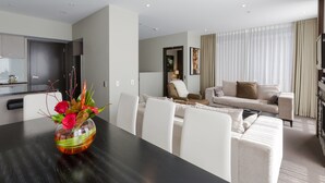 A modern hotel room with a dining area, a sofa, and a TV. - Queenstown Village Apartments (Kawarau Falls)