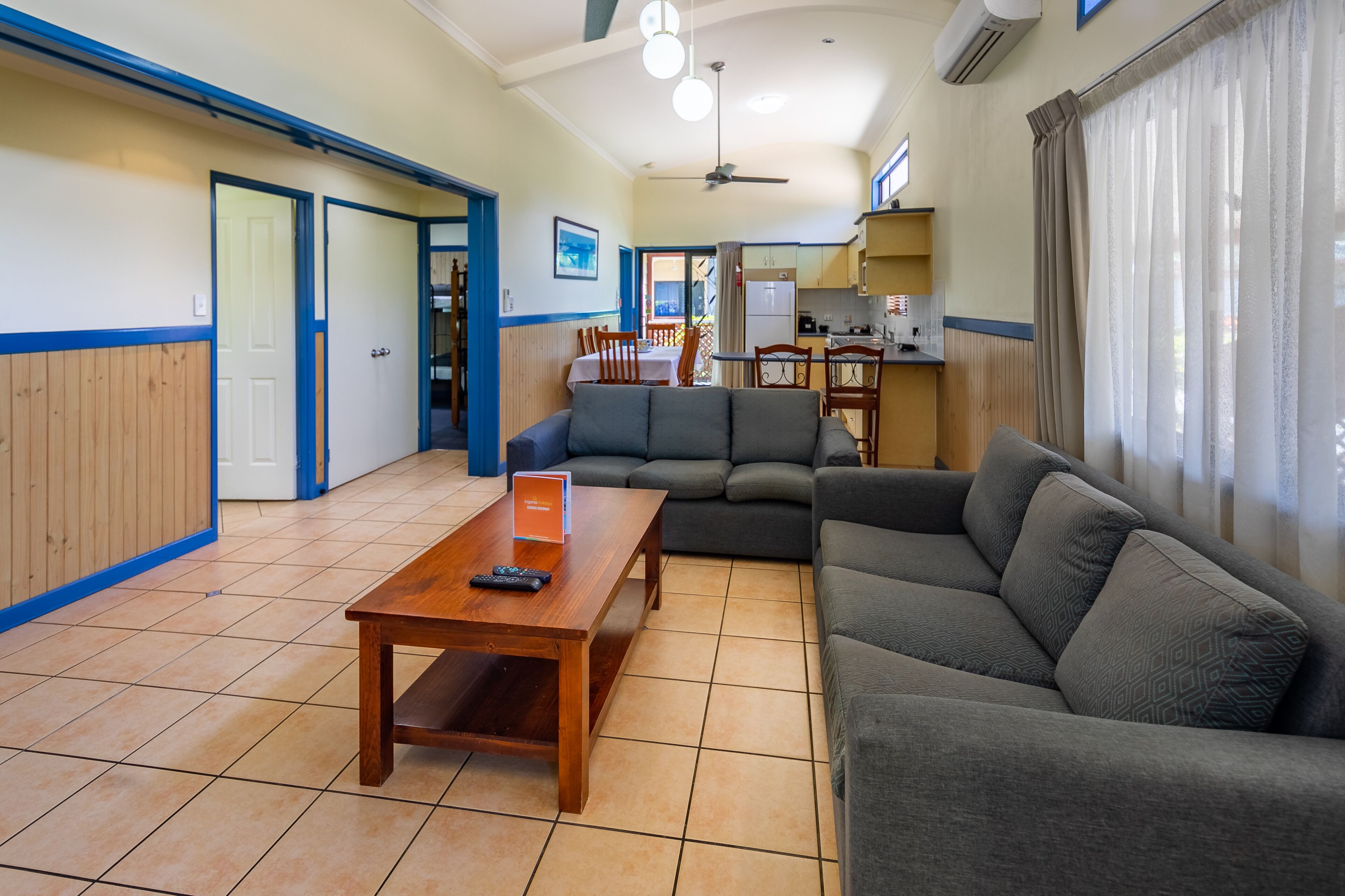 A spacious living area with a sofa, a wooden coffee table, and a dining table.