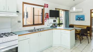 A modern kitchen with white cabinets, a gas stove, a microwave, and a sink.