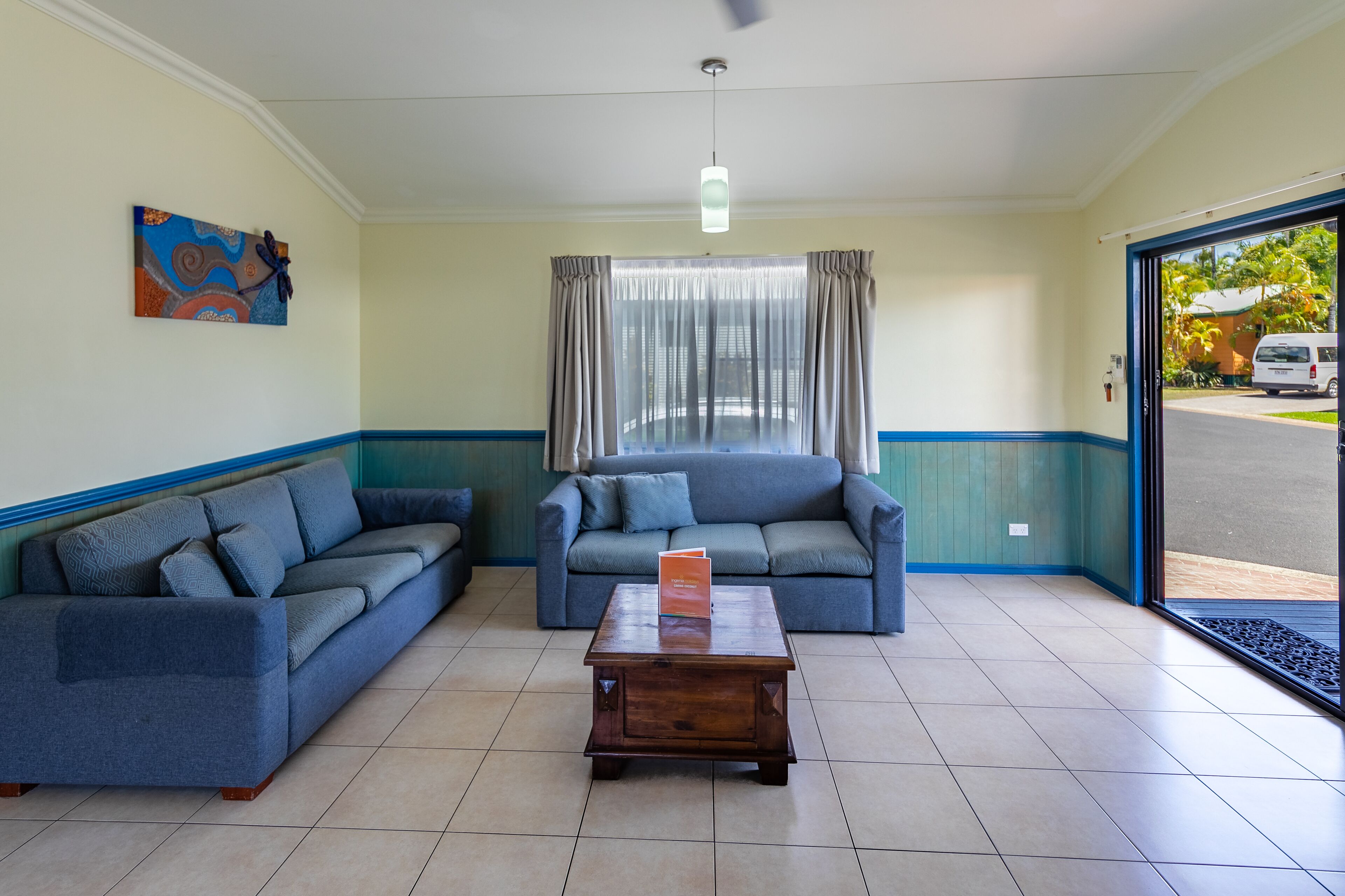 A room with two sofas, a wooden coffee table, and a window with curtains.