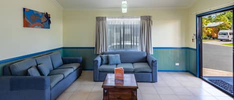 A room with two sofas, a wooden coffee table, and a window with curtains.