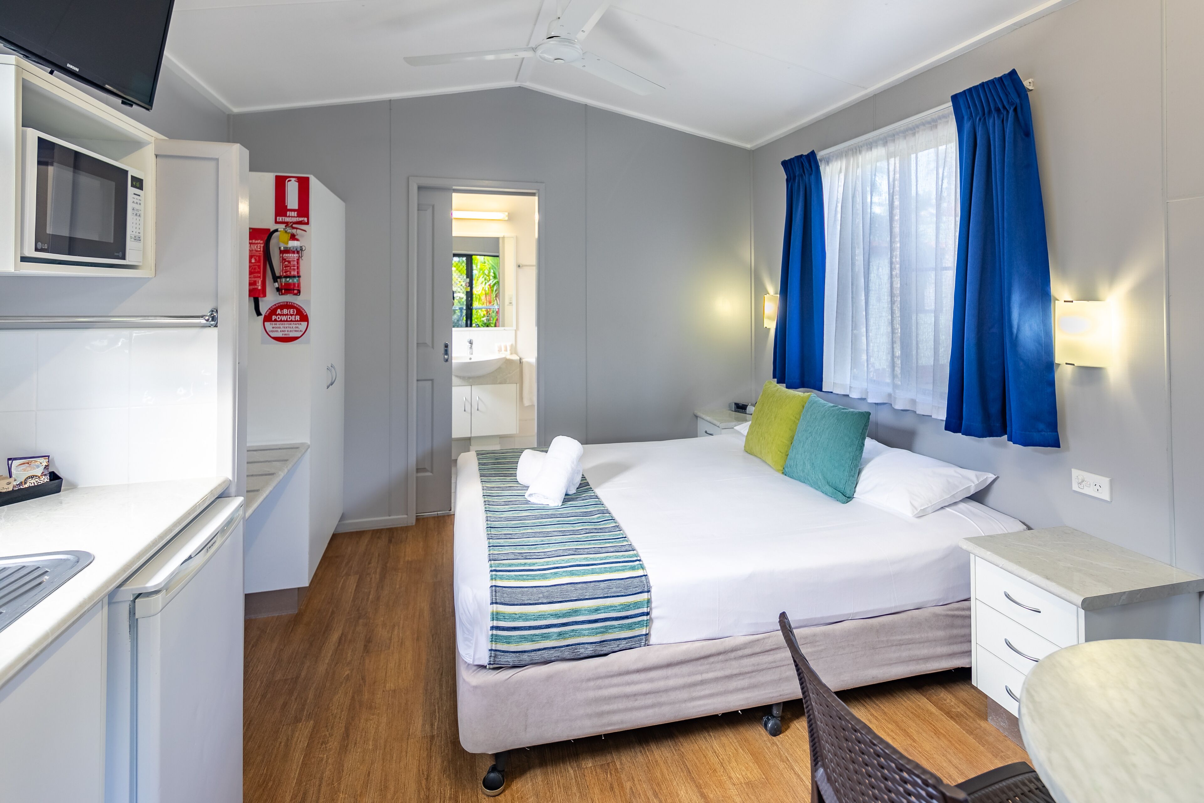 A hotel room with a bed, bedside table, and a built-in microwave.