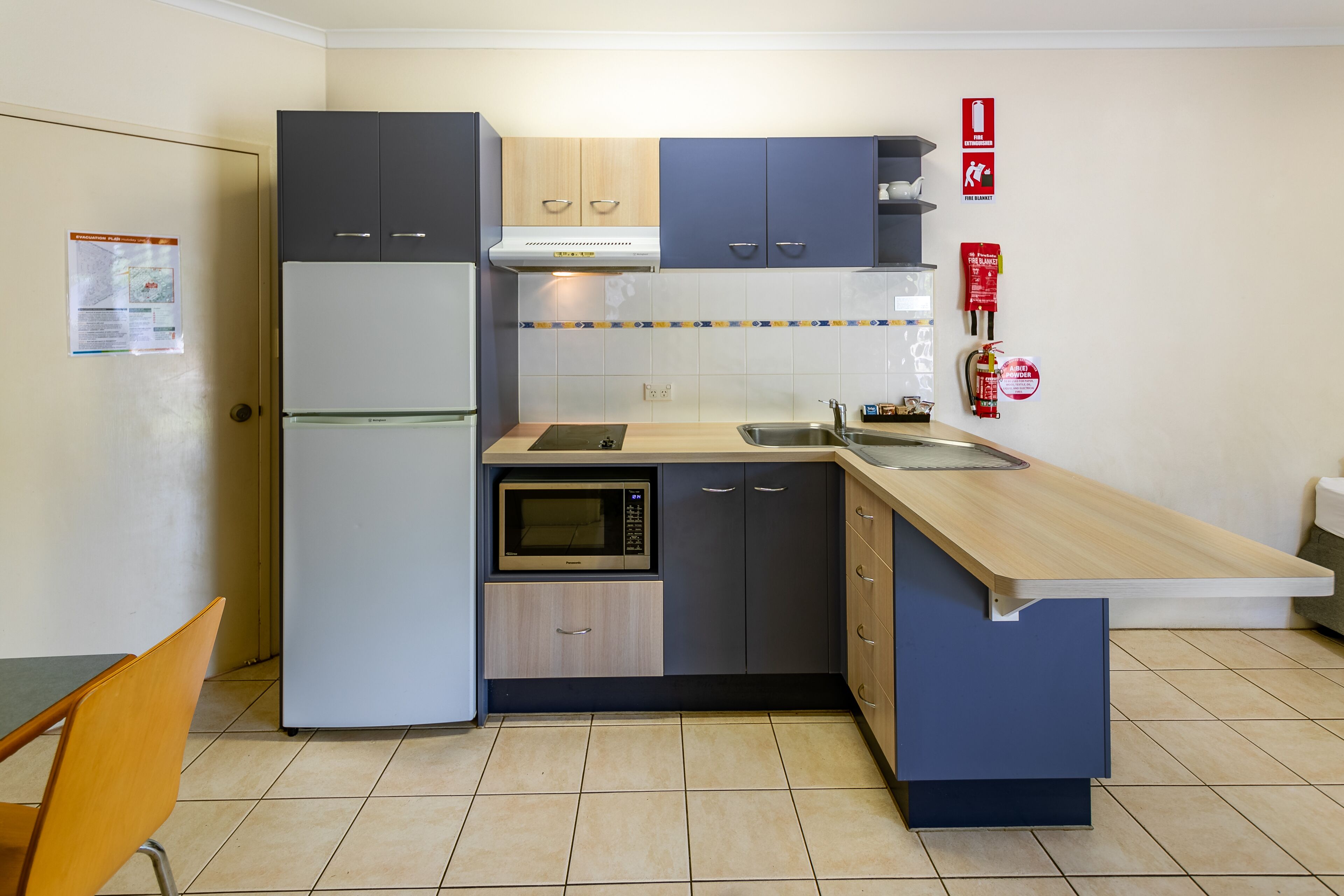 A compact kitchen with a refrigerator, microwave, and sink.