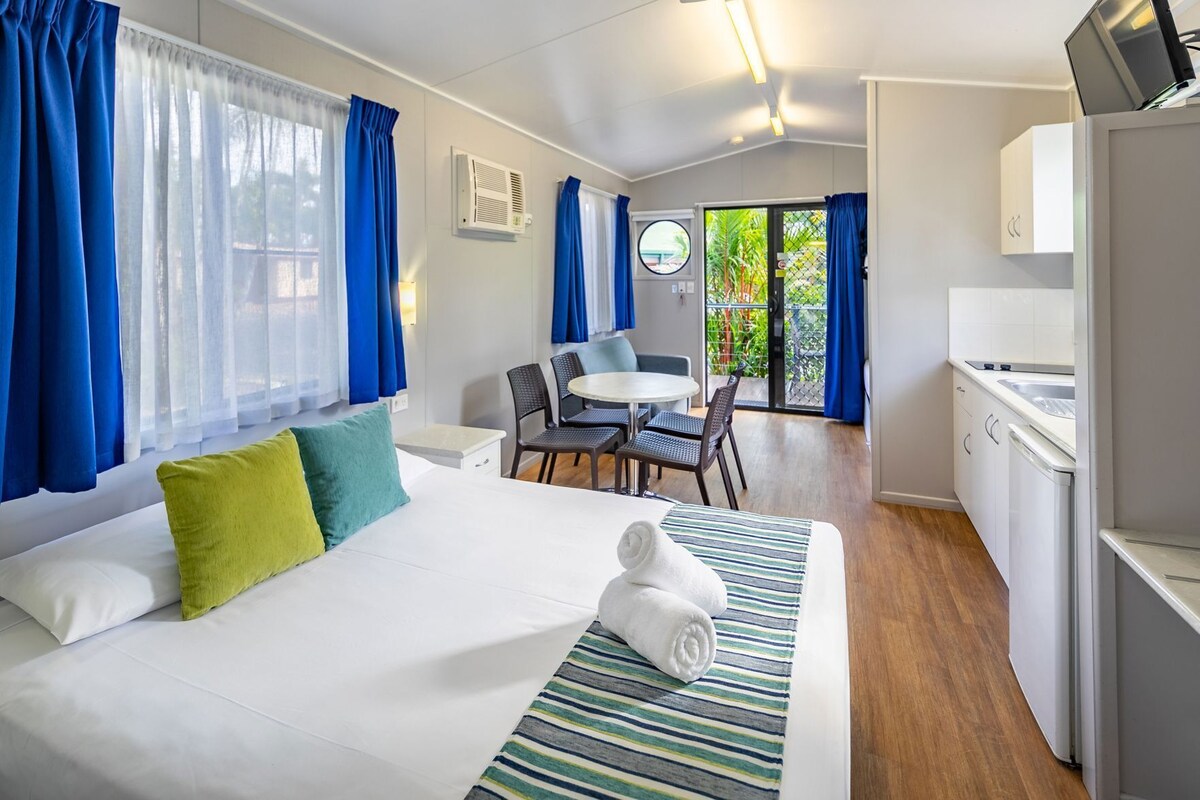 Una habitación de hotel con una cama, un pequeño comedor y una kitchenette.