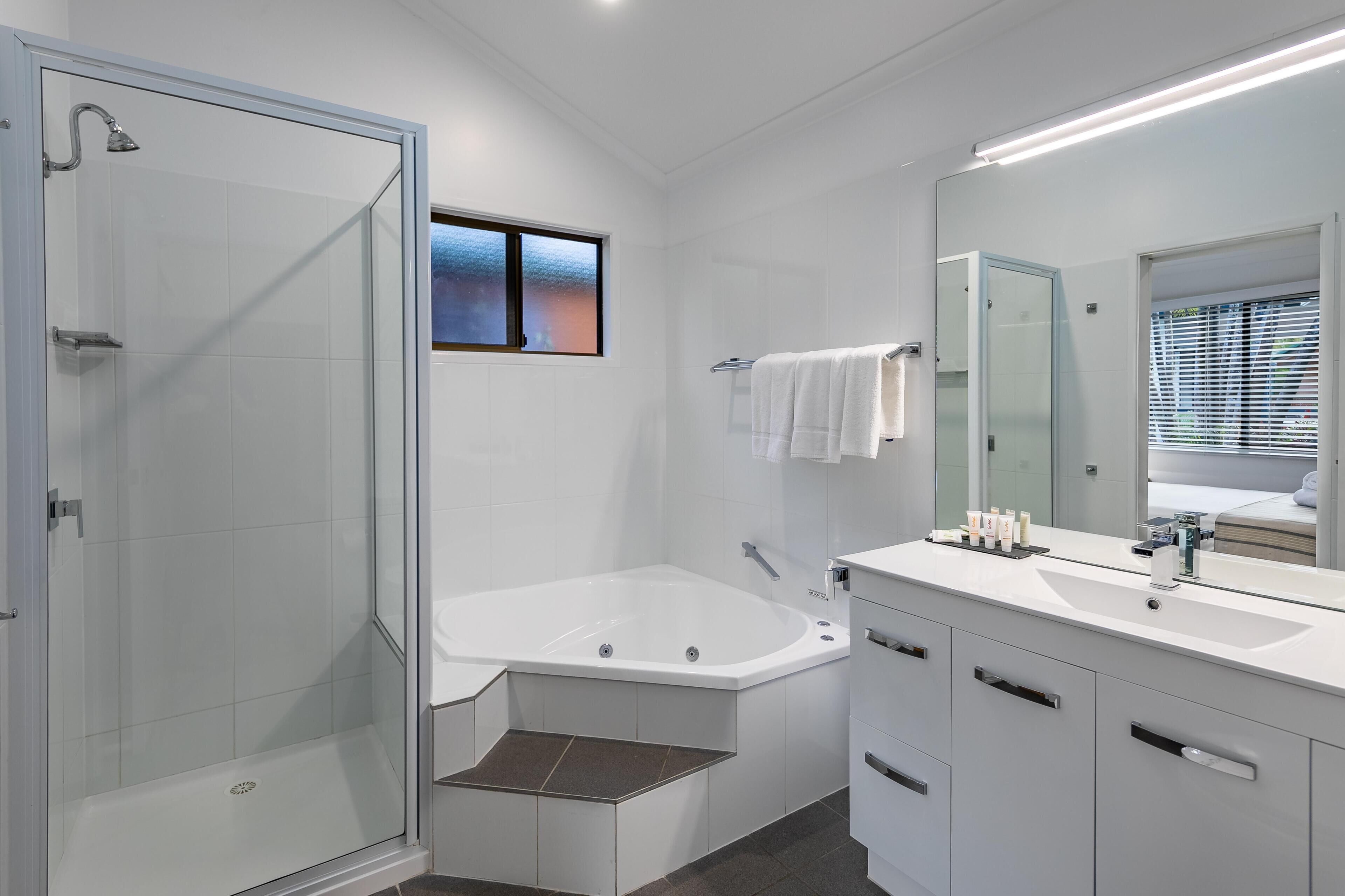 A modern bathroom with a glass-enclosed shower, a freestanding bathtub, and a vanity with a large mirror.