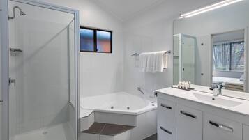A modern bathroom with a glass-enclosed shower, a freestanding bathtub, and a vanity with a large mirror.