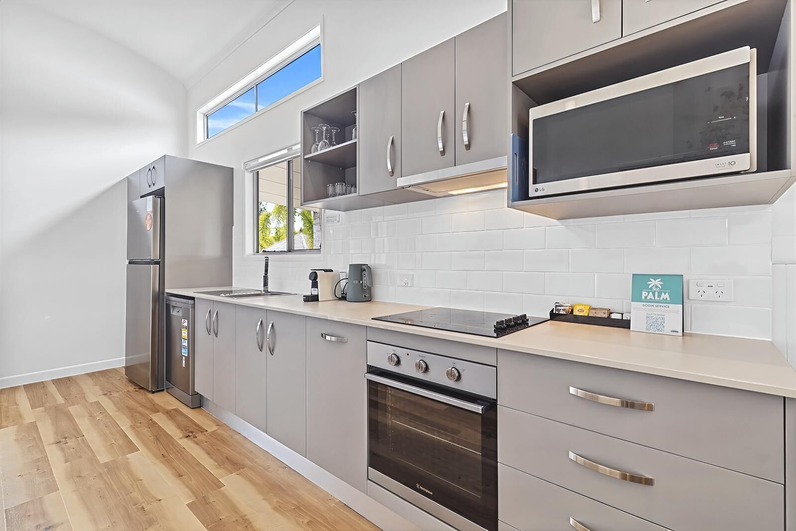 A modern kitchen with grey cabinetry, a built-in microwave, a stove, and a dishwasher.
