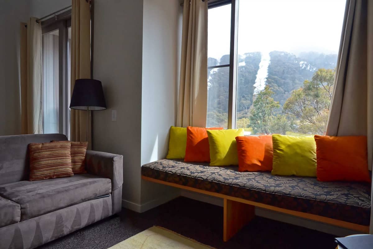 A room with a sofa and a window seat with cushions.