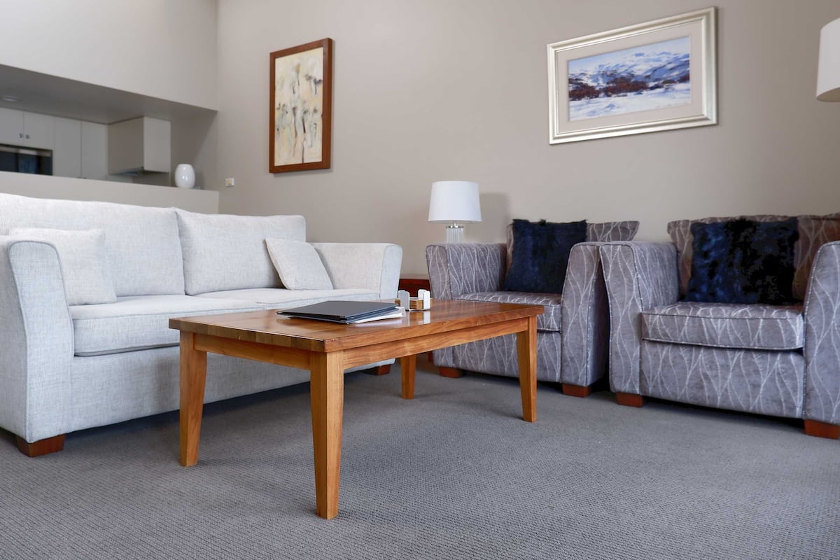 A modern living room with a light grey sofa, a patterned grey sofa, and a wooden coffee table.