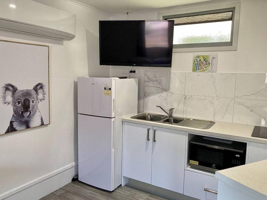 A modern kitchen with white cabinetry, a built-in microwave, and a large window above the sink.