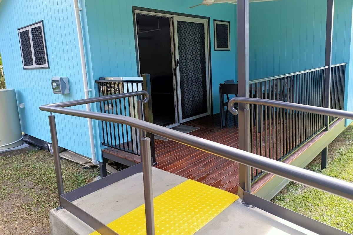 A blue building with a covered porch, a sliding glass door, and a small table with chairs.