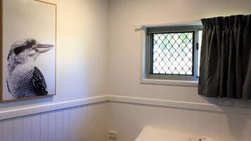 A bedroom with a bed, a ceiling fan, a window with curtains, and a wall-mounted picture.