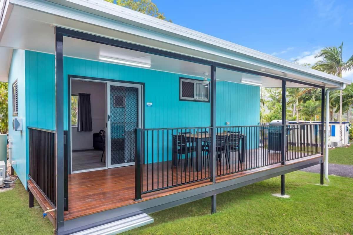 A turquoise building with a wooden deck and a covered patio area.