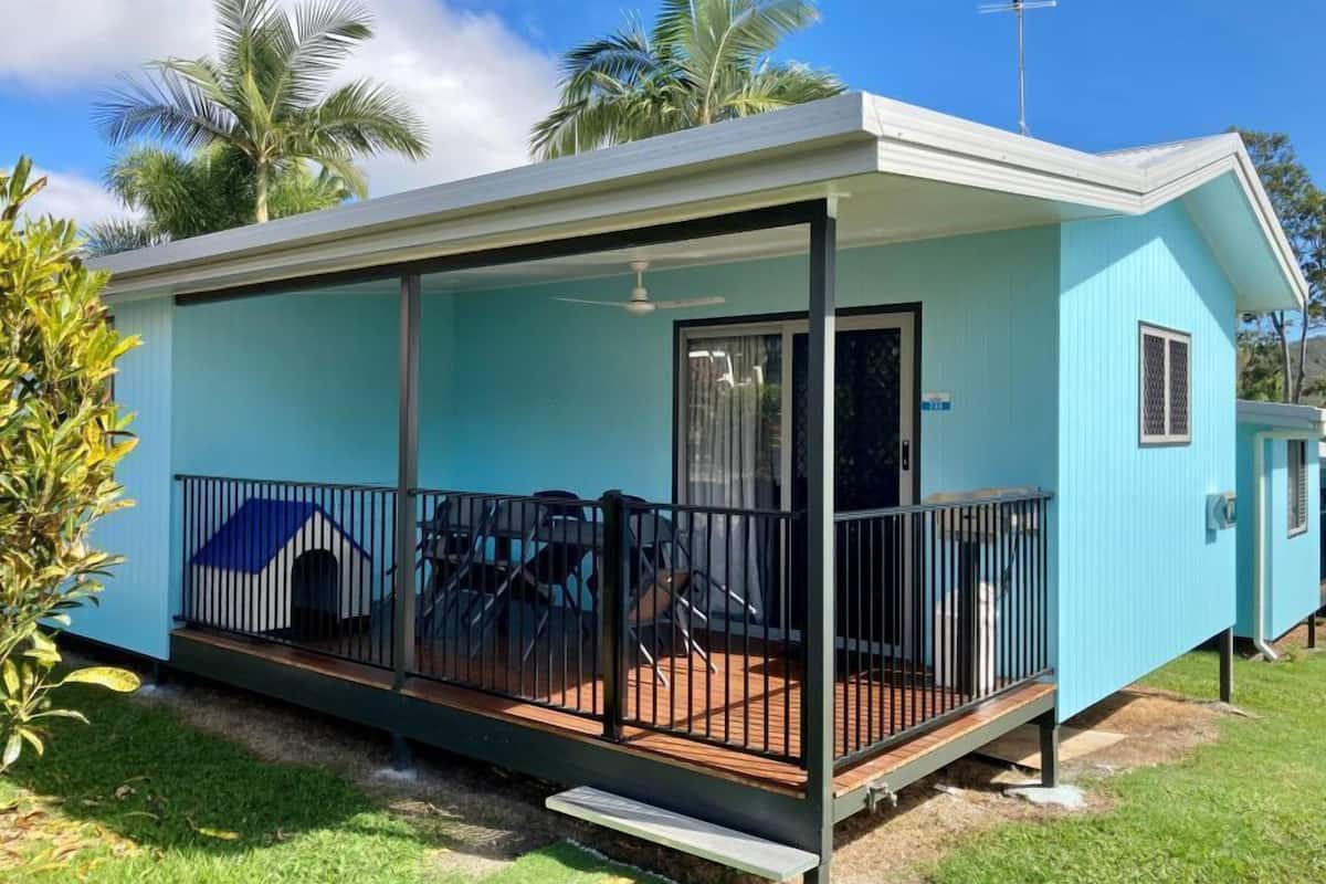A small, single-story building with a covered porch, a sliding glass door, and a small deck area.