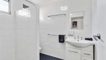 Un bagno moderno con piastrelle bianche, un lavandino, uno specchio e un porta asciugamani.