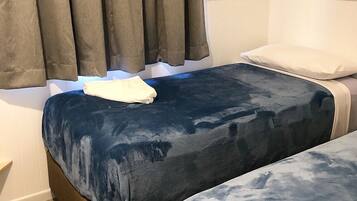 A room with two beds, a dark blue bedspread, a white pillow, and a brown headboard.